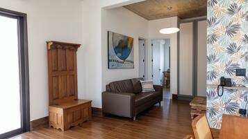 A modern living room with a wooden bench, a leather sofa, and a dining area with a wooden table and chairs.