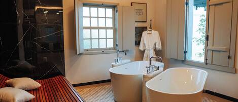 A modern bathroom with a freestanding bathtub, a large window, and a wooden bench.