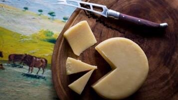 A wooden board with cheese and a cheese knife.