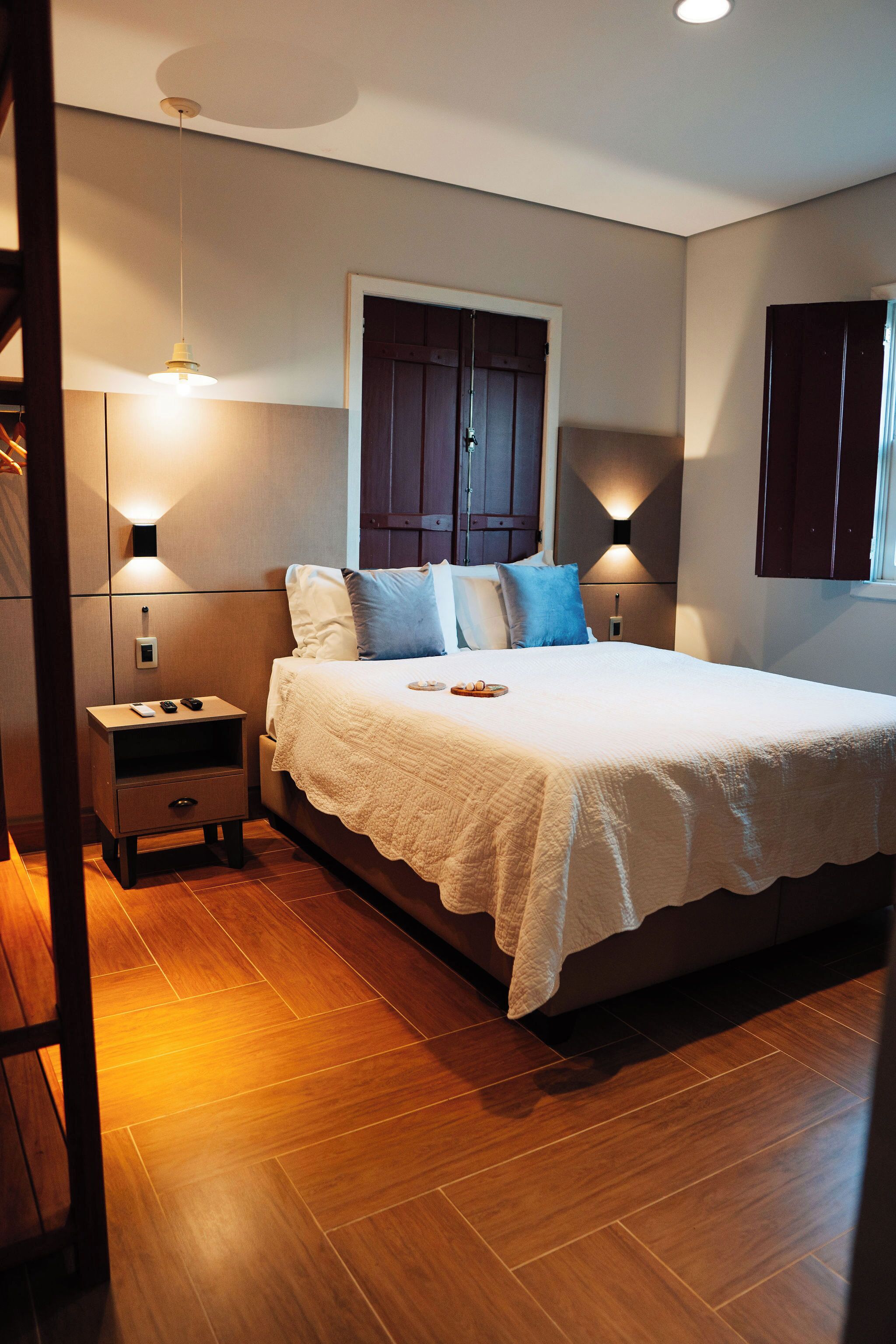 A bedroom with a large bed, two bedside tables, a wardrobe, and a window.