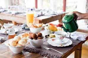 A breakfast table with various food items, a coffee pot, and a pitcher of orange juice. - Pousada Pequena Tiradentes (Tiradentes)