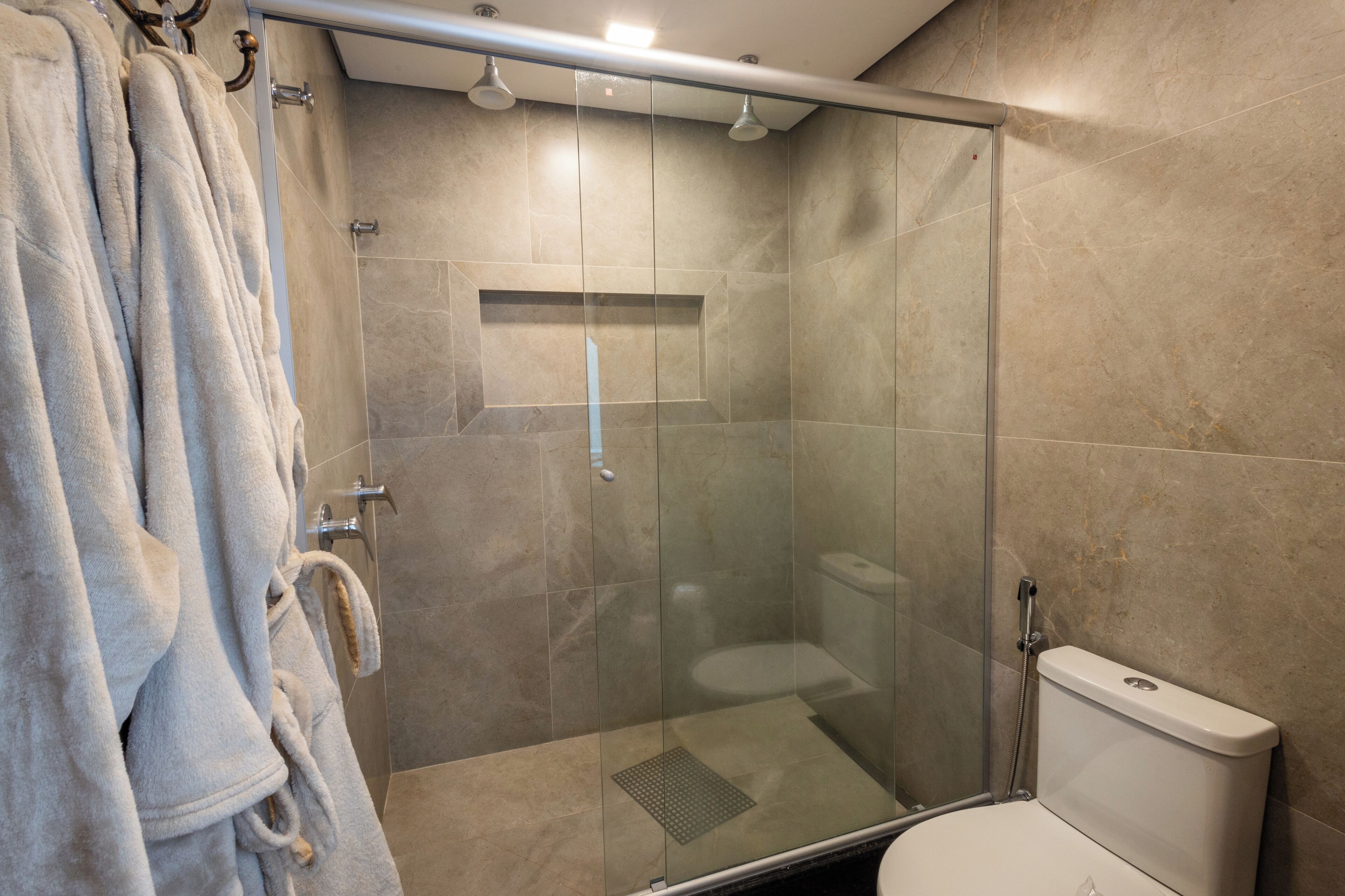 Un baño con ducha de vidrio, inodoro y un perchero con toallas.