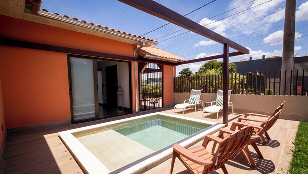 A swimming pool with a wooden deck, outdoor furniture, and a covered patio area. - Pousada Pequena Tiradentes (Tiradentes)