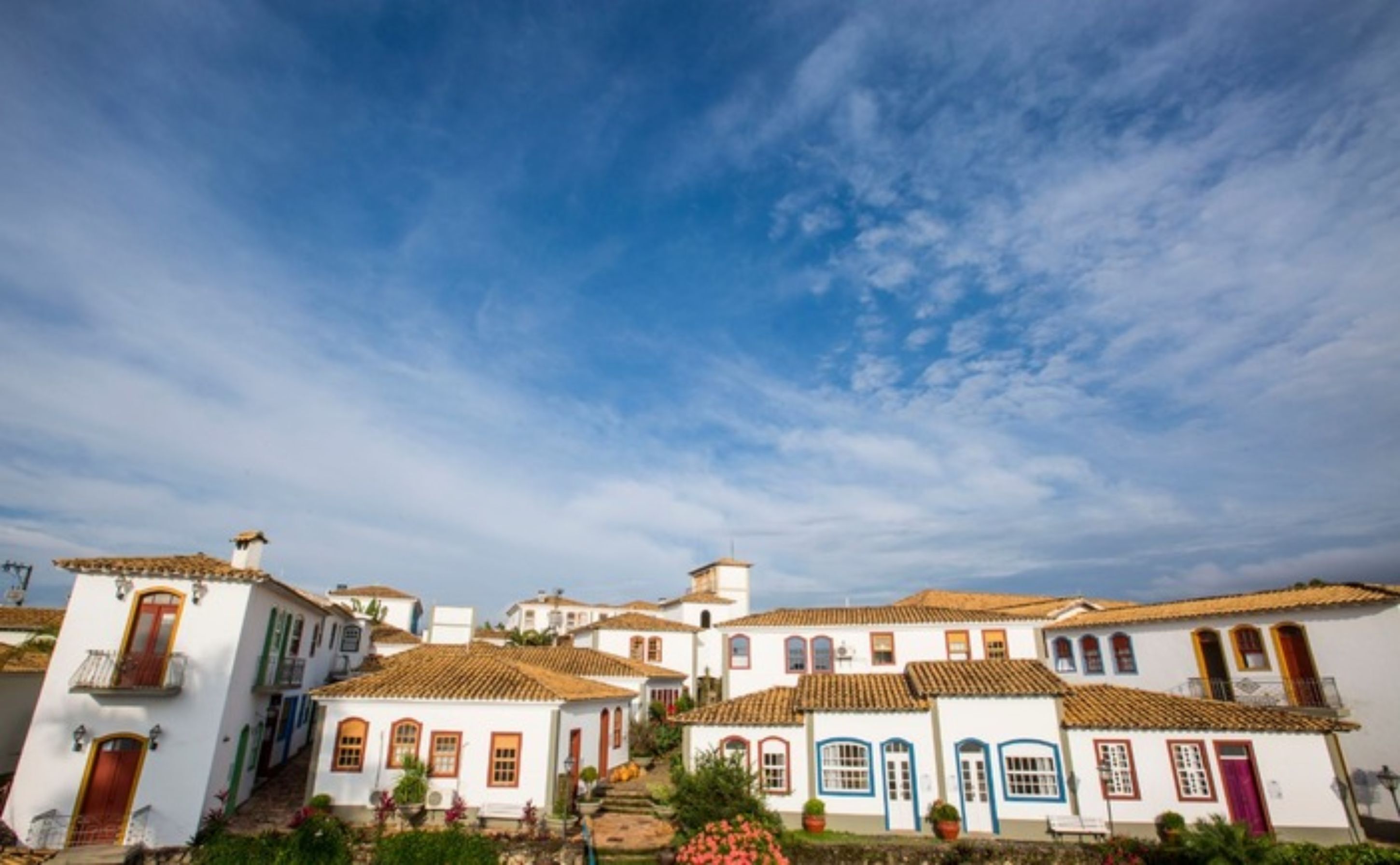 Un conjunto de edificios blancos con tejados de teja rojiza y puertas de colores, característico de la arquitectura mediterránea.