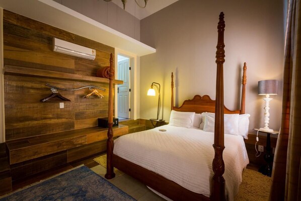 A four-poster bed with a wooden headboard, a wooden wardrobe with a mirror, and a bedside table with a lamp. - Pousada Pequena Tiradentes (Tiradentes)