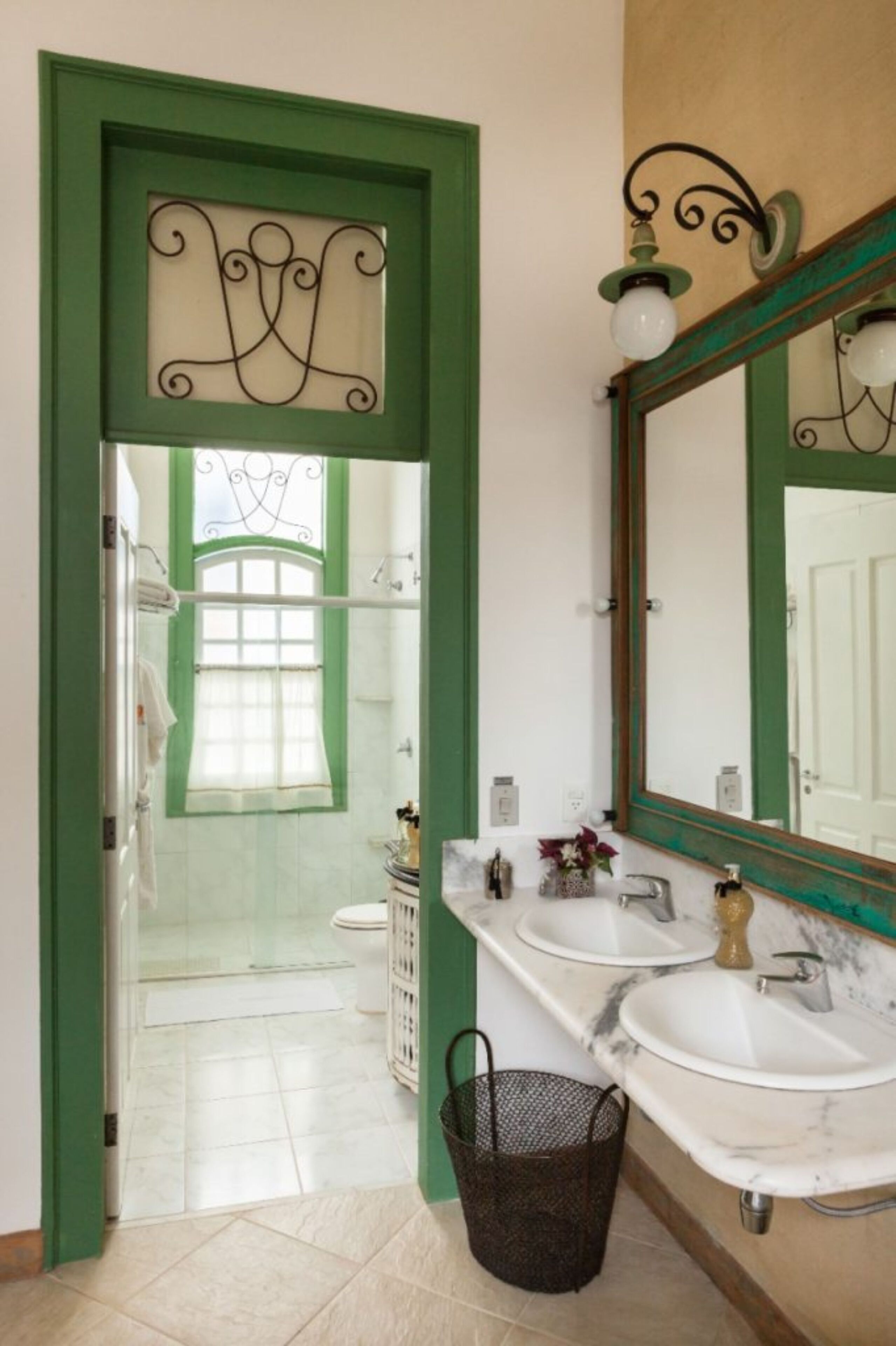 A bathroom with two sinks, a mirror, and a window with a curtain.