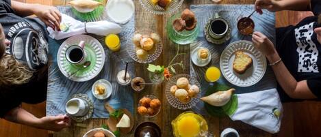 Una mesa de madera con diversos alimentos para el desayuno, como pasteles, frutas y bebidas.