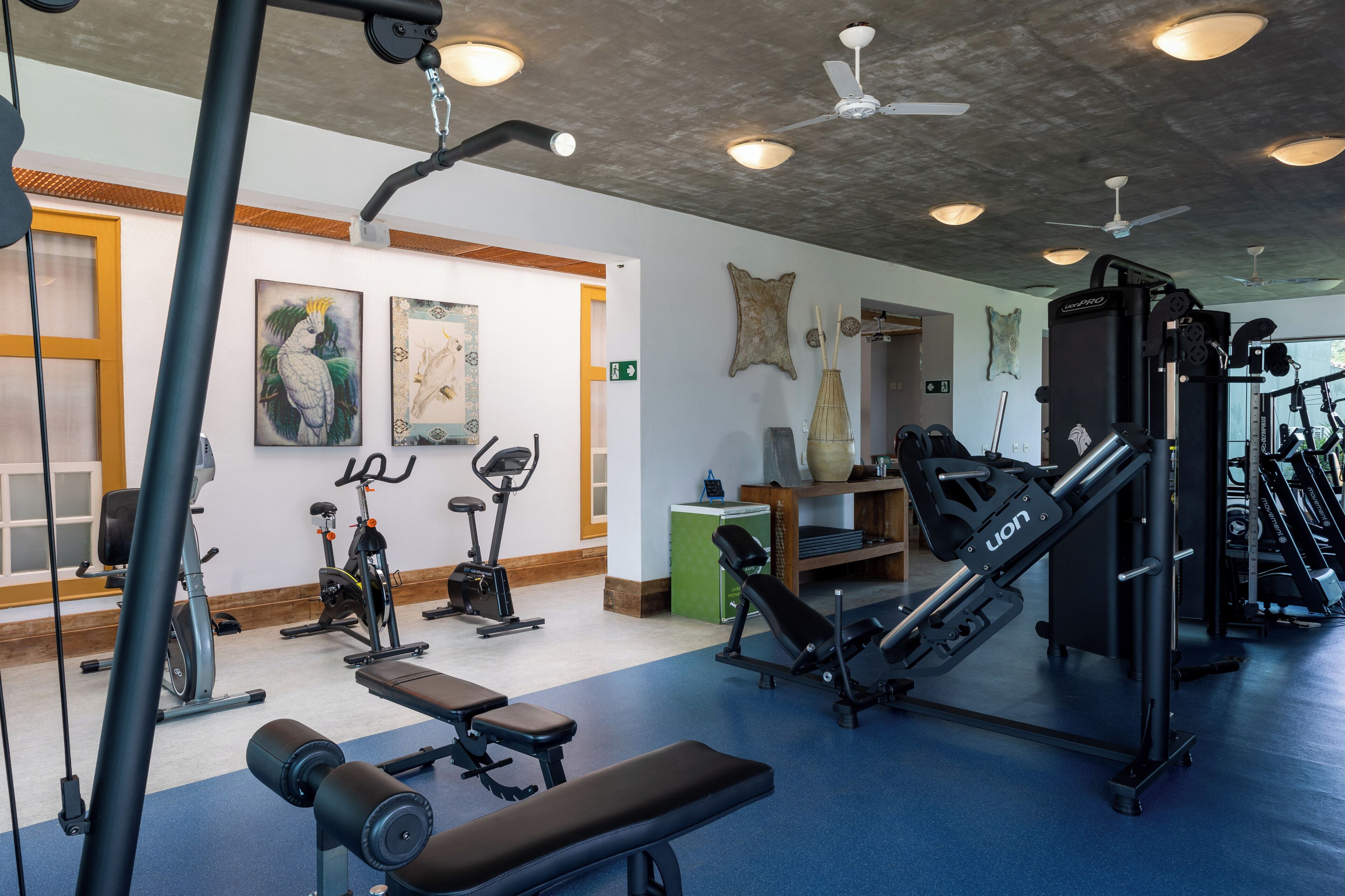 Un gimnasio con equipo de ejercicio, una banca y arte en la pared.