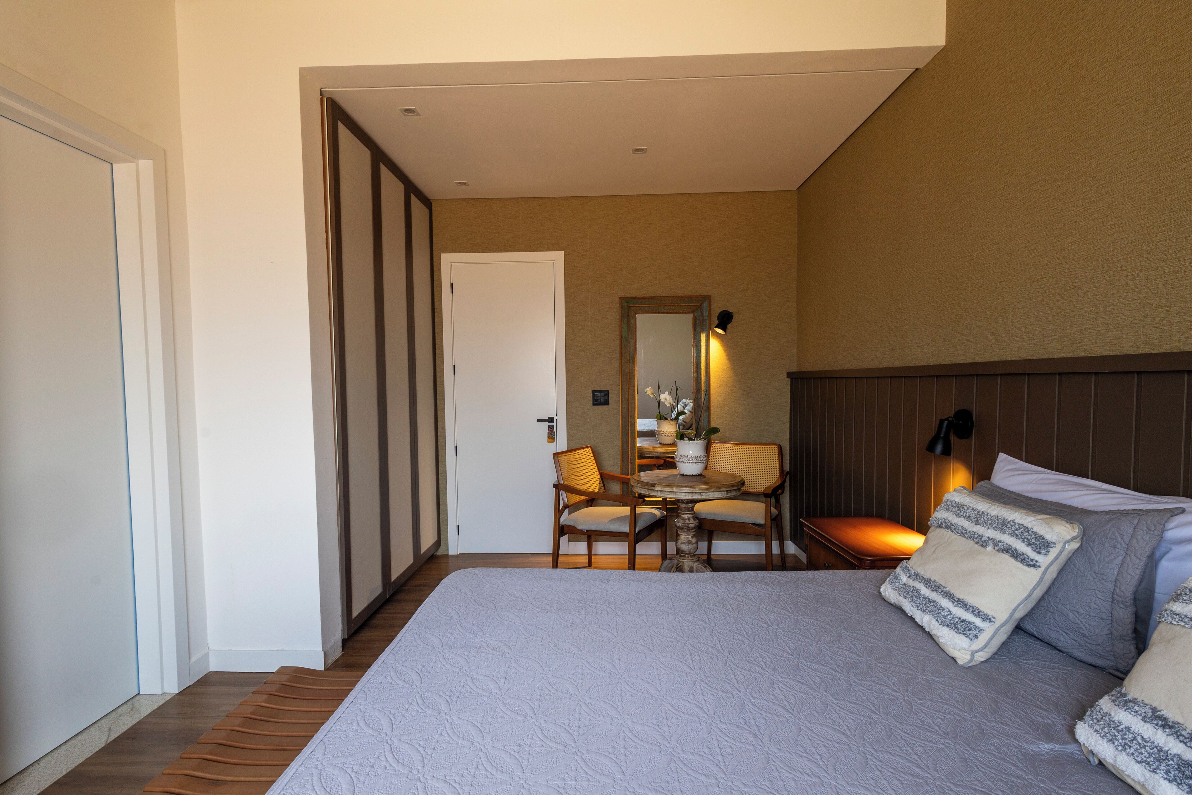 Een slaapkamer met een groot bed, een nachtkastje, een stoel en een spiegel.