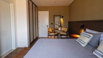 Een slaapkamer met een groot bed, een nachtkastje, een stoel en een spiegel.