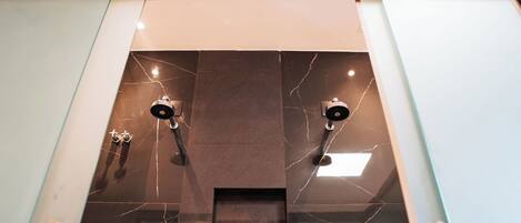 Un bagno moderno con rivestimento in marmo e due soffioni.