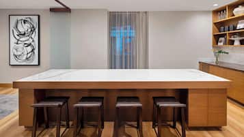 A modern kitchen with a large island, wooden stools, and a framed artwork on the wall.