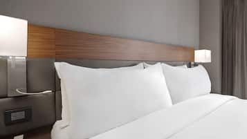 A hotel room with a neatly made bed, a wooden headboard, bedside lamps, and a power outlet.