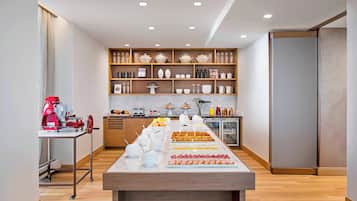 A modern kitchen with a marble countertop, wooden shelves, and a variety of kitchenware.