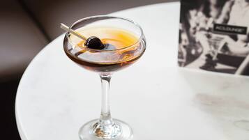 A cocktail in a martini glass on a white table.