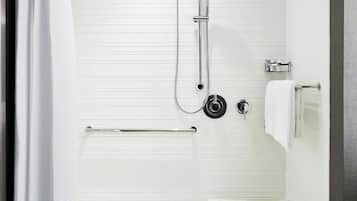 A modern shower area with a handheld showerhead, a handheld showerhead, and a handheld showerhead.