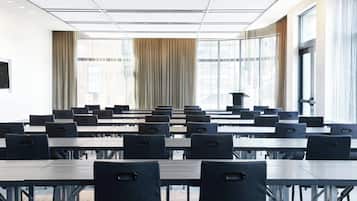 A conference room with multiple tables and chairs, large windows with curtains, and a modern ceiling design.