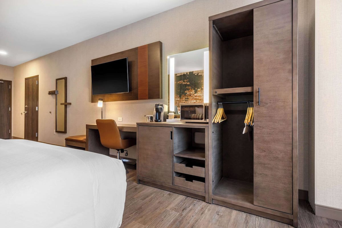 Ein modernes Hotelzimmer mit einem großen Bett, einem Schreibtisch mit einem Flachbildfernseher, einem Spiegel, einem Kamin und einem Kleiderschrank mit Spiegel.