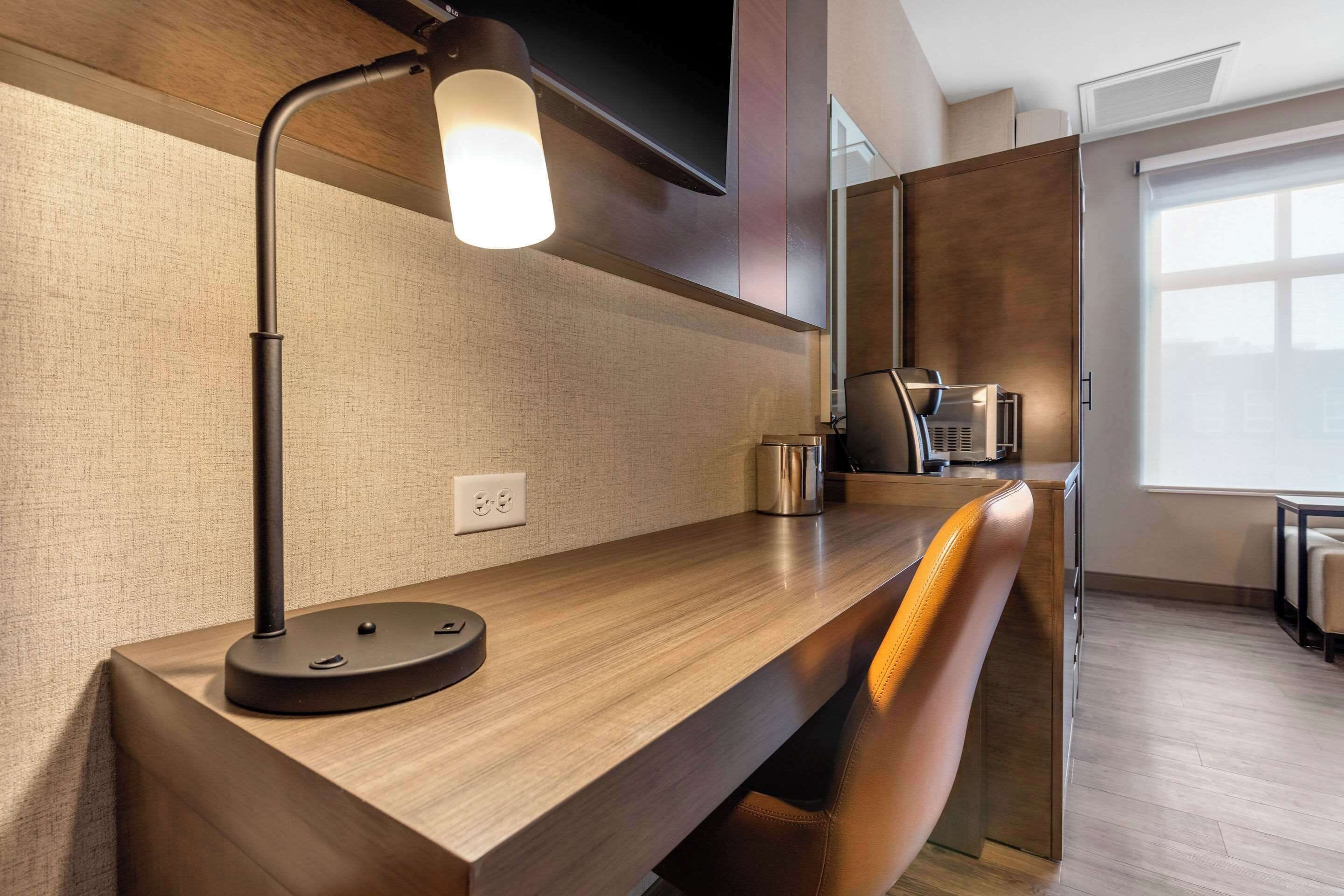 Una cocina moderna con encimera de madera, cafetera integrada y una lámpara colgante elegante.