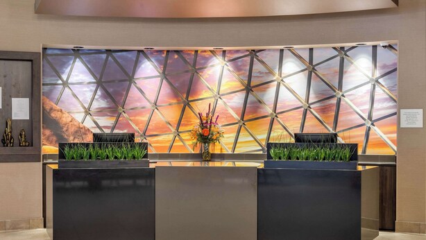 Een receptiebalie met een geometrisch wandontwerp en uitzicht op een zonsondergang.