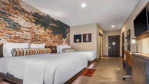 Een hotelkamer met een groot bed, een bureau en een bakstenen muur.