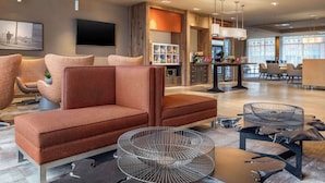 Een moderne hotellobby met een zithoek, een bar en een televisie.