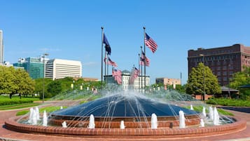 A fountain with multiple water jets in a circular brick basin, surrounded by a brick walkway.