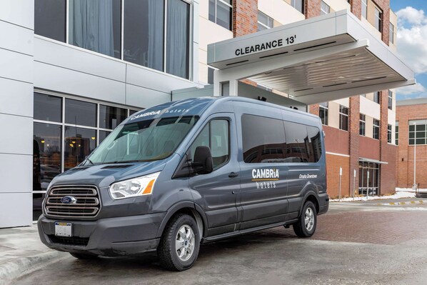 A gray van parked in front of a hotel with a sign reading "CAMBRIA hotels" and "Clearance 13'".