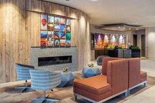 Un hall d’entrée moderne avec un mur en bois, une cheminée et un espace détente comprenant un canapé et des fauteuils.