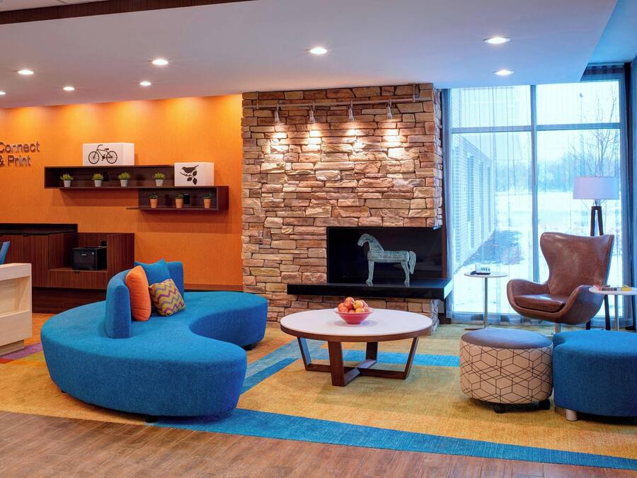 Un vestíbulo moderno con chimenea de piedra, asientos azules y un letrero que dice 'Connect & Print'.