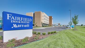 Señal de Fairfield Inn & Suites Marriott con un estacionamiento y edificios al fondo.