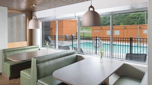 A poolside seating area with green cushioned benches and a table, overlooking a swimming pool with a 'No Diving' sign. - Fairfield Inn & Suites Athens Marriott (Athens)