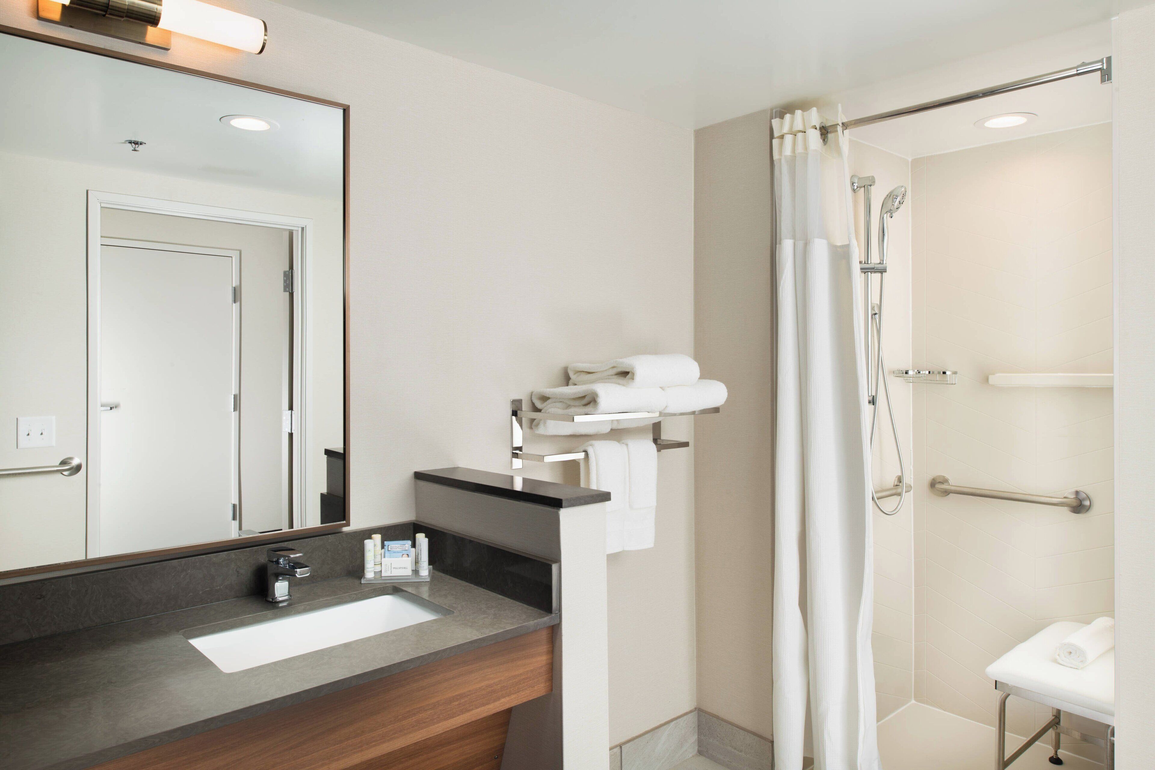 Un baño moderno con lavamanos, espejo y zona de ducha.
