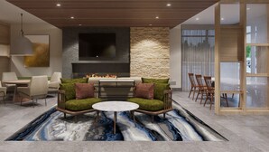 A modern living room with a fireplace, comfortable seating, and a large TV. - Fairfield Inn & Suites Athens Marriott (Athens)