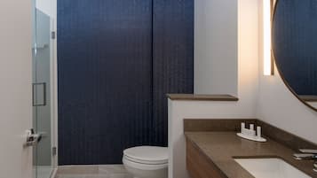Une salle de bain moderne avec une douche à parois de verre, des toilettes blanches et un meuble-lavabo avec un miroir.