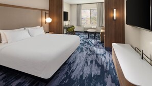 A hotel room with a large bed, a desk with a chair, a TV, and a large window with curtains.