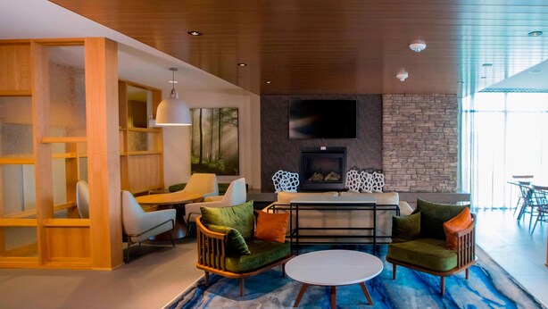 A modern living room with a fireplace, wooden furniture, and a large window.