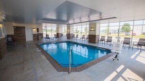 An indoor swimming pool with clear water, surrounded by chairs and a 'No Jumping' sign.