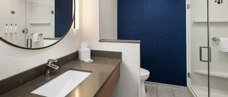 A modern bathroom with a large mirror, a sink, and a shower area.