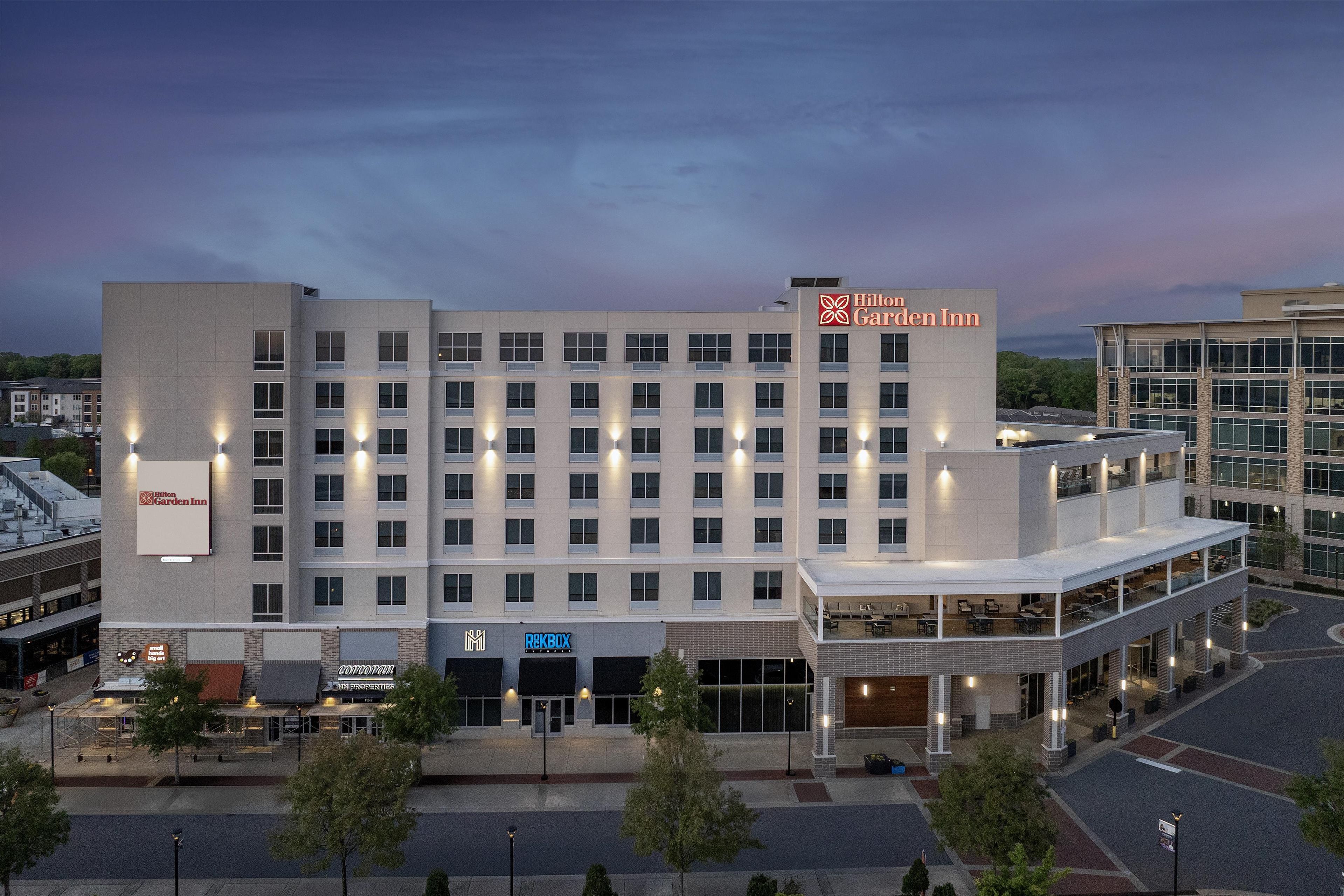 Een meerhoog hotel met een opvallend Hilton Garden Inn bord, een restaurant op de begane grond en een parkeerplaats.