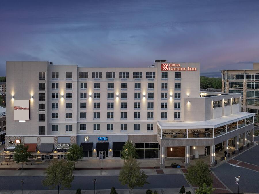 Een meerhoog hotel met een opvallend Hilton Garden Inn bord, een restaurant op de begane grond en een parkeerplaats.
