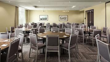 A conference room with multiple tables and chairs, arranged in a U-shape.