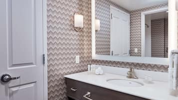 A bathroom with a white sink, dark wooden vanity, and a mirror with wall-mounted lights.