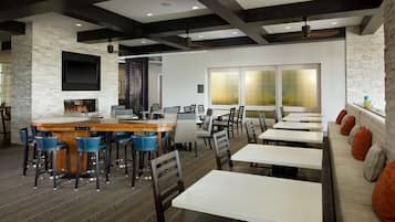Un restaurante moderno con pared de piedra, zona de bar y diferentes disposiciones de asientos.
