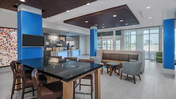 A modern lobby with a reception desk, seating area, and a large window providing a view of the outdoors.