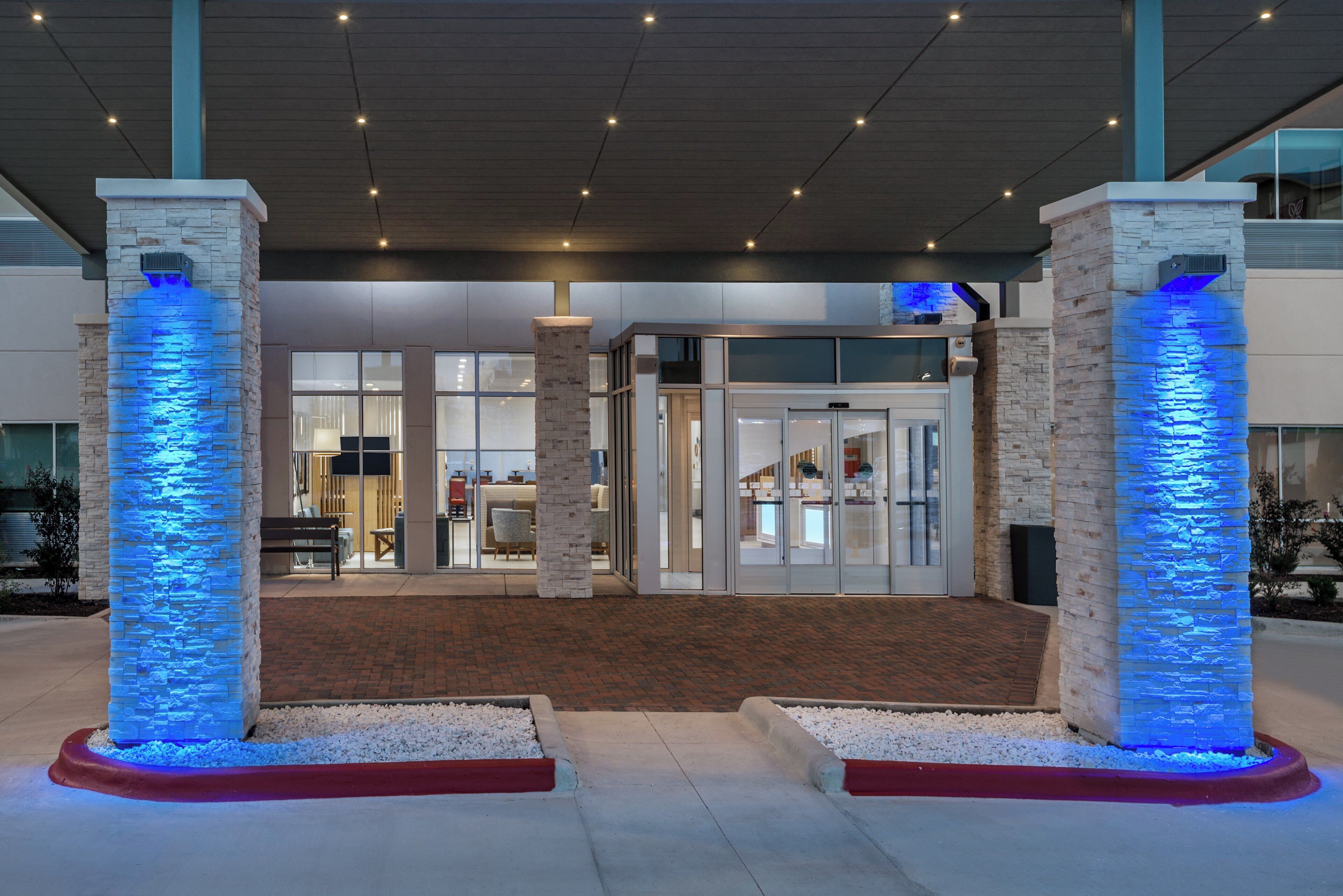 A hotel entrance with a modern design, featuring a brick facade and illuminated pillars.