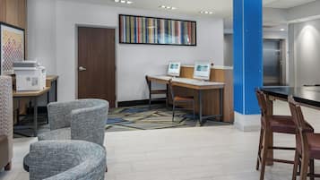 Un hall de hotel con mostrador de recepción, zona de estar y un pilar azul grande.
