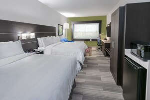 A hotel room with two beds, a desk, a chair, a microwave, and a refrigerator.