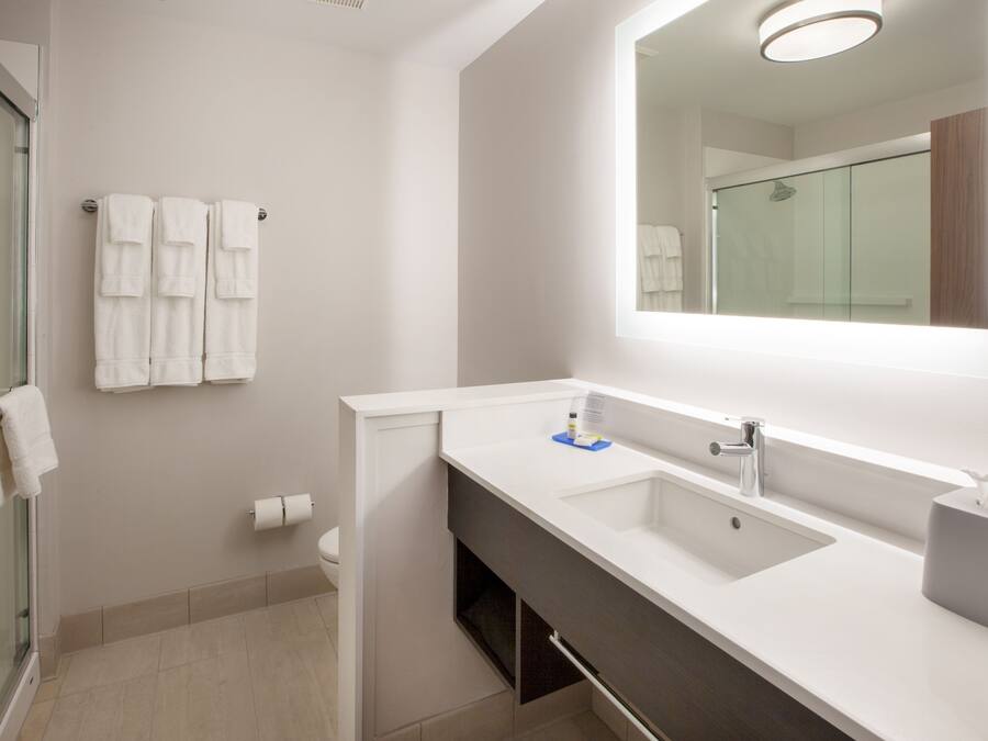 Ein modernes Badezimmer mit Glasdusche, weißem Waschbecken und einem großen Spiegel.