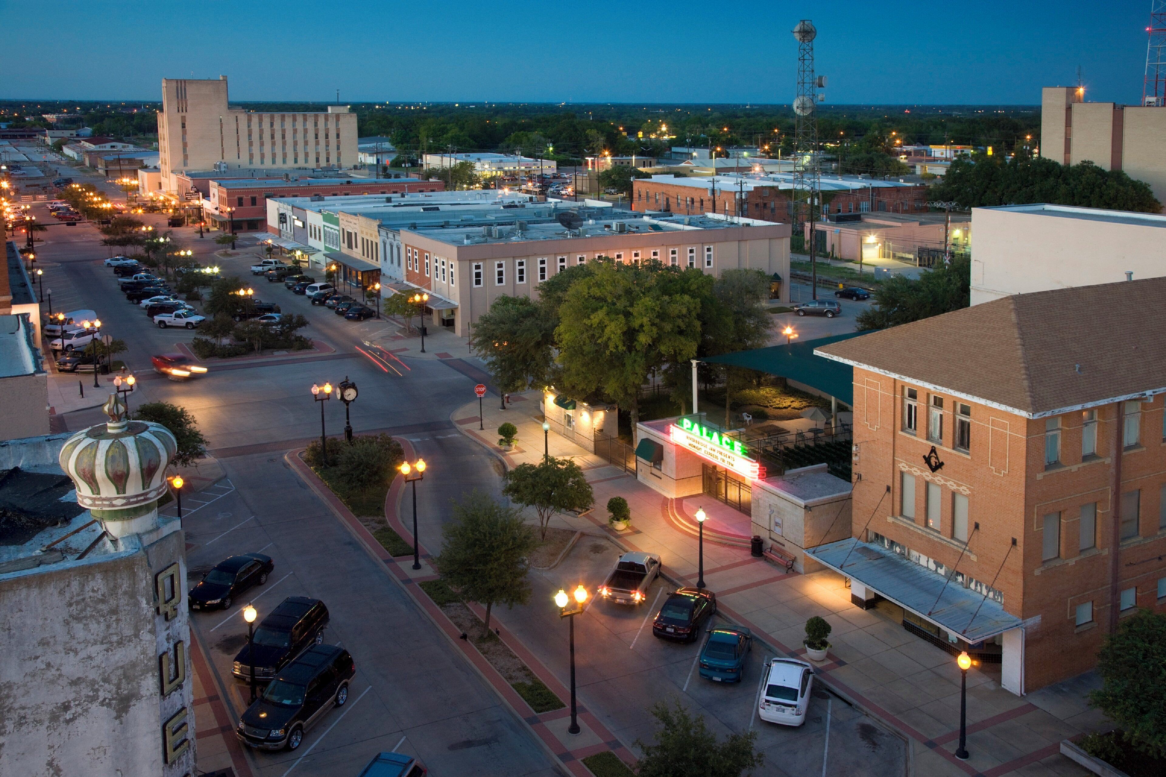 A cityscape with a prominent building labeled 'PALACE' and a parking lot with several cars.